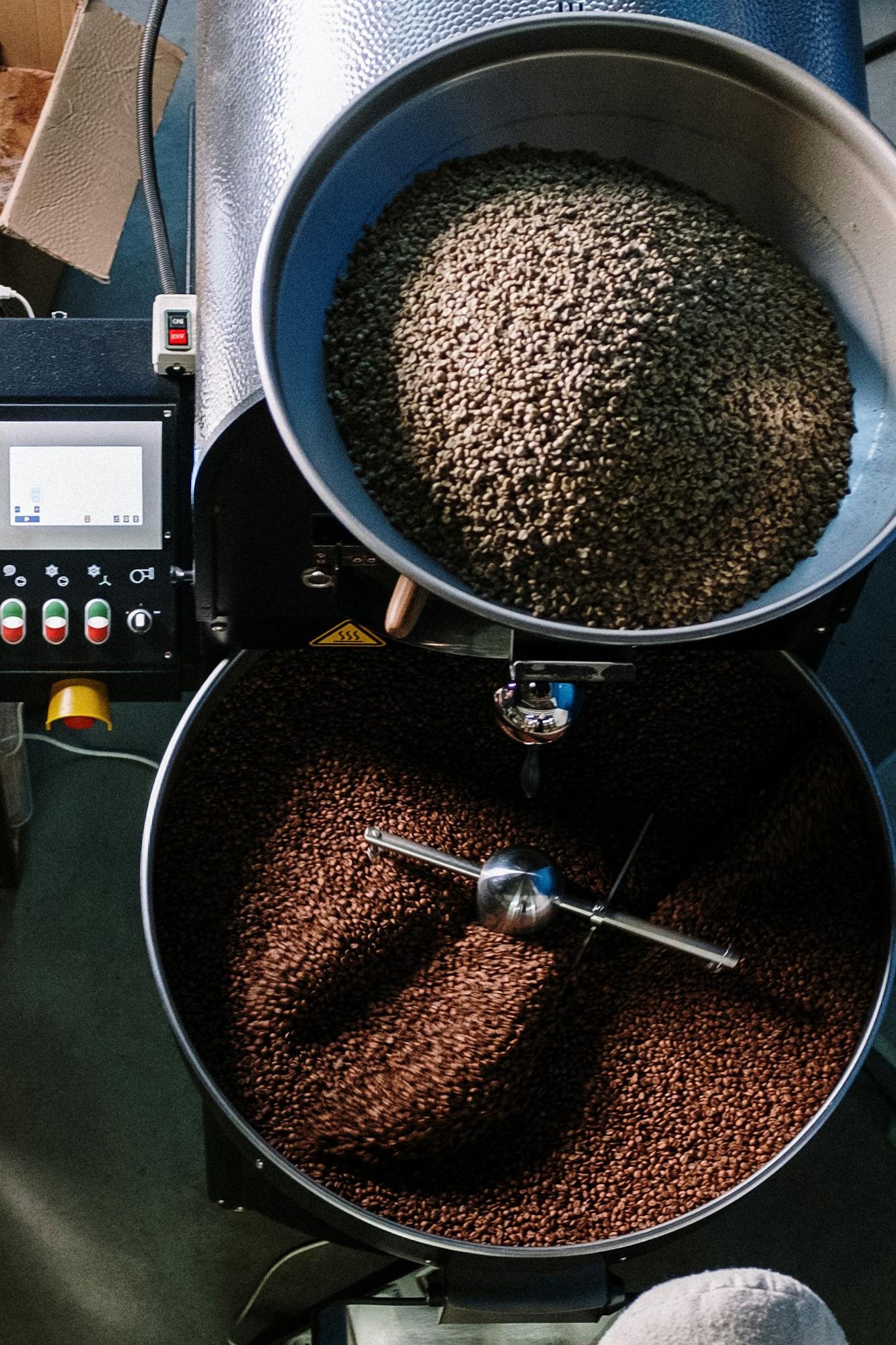 Top view of a coffee roasting machine processing beans in a workshop.